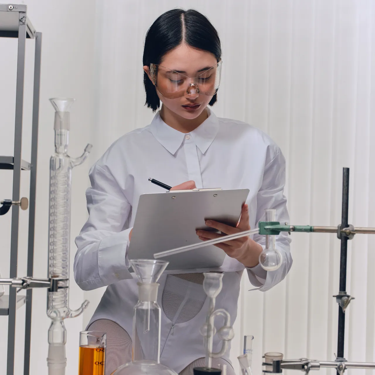 A scientist in a lab taking notes on a clipboard.