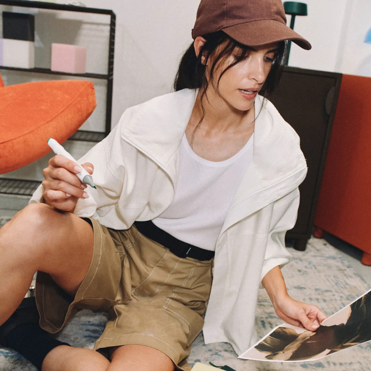 A woman sitting on the floor, choosing between printed versions of a design.